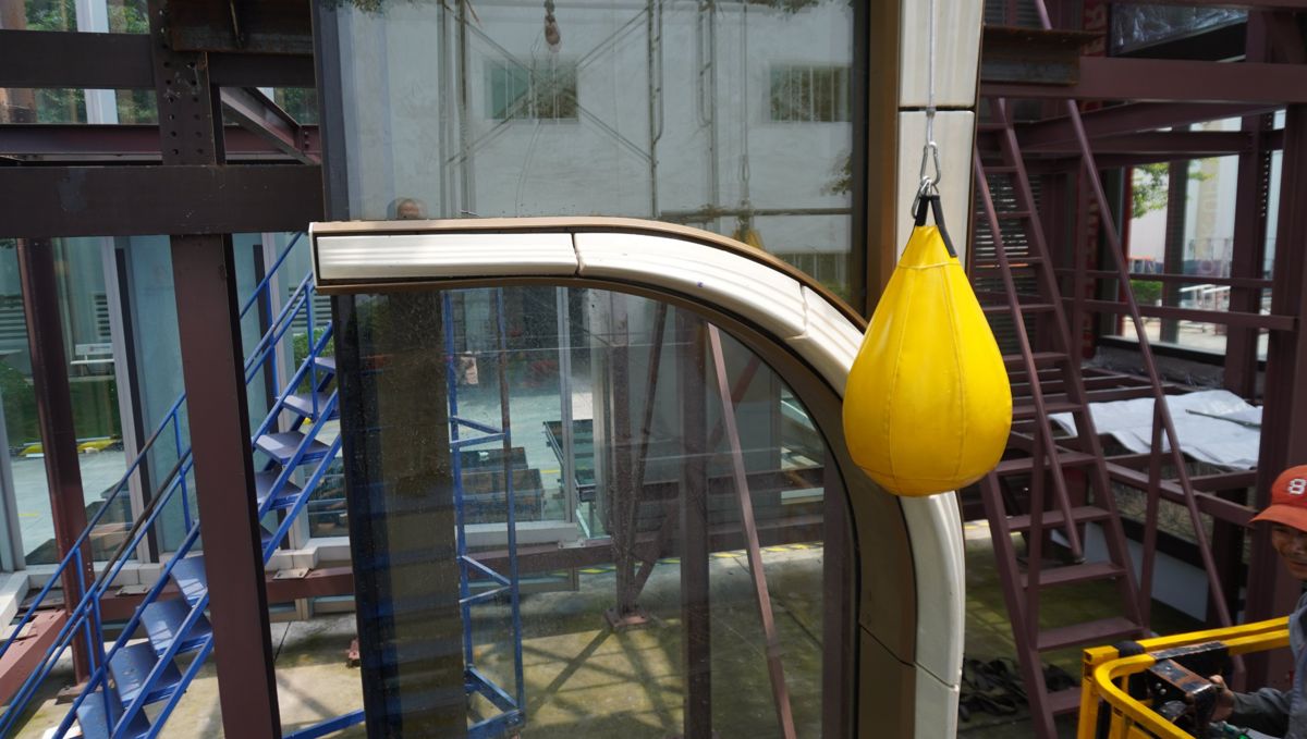 Soft-body bag impactor suspended beside a terracotta sunshade sample